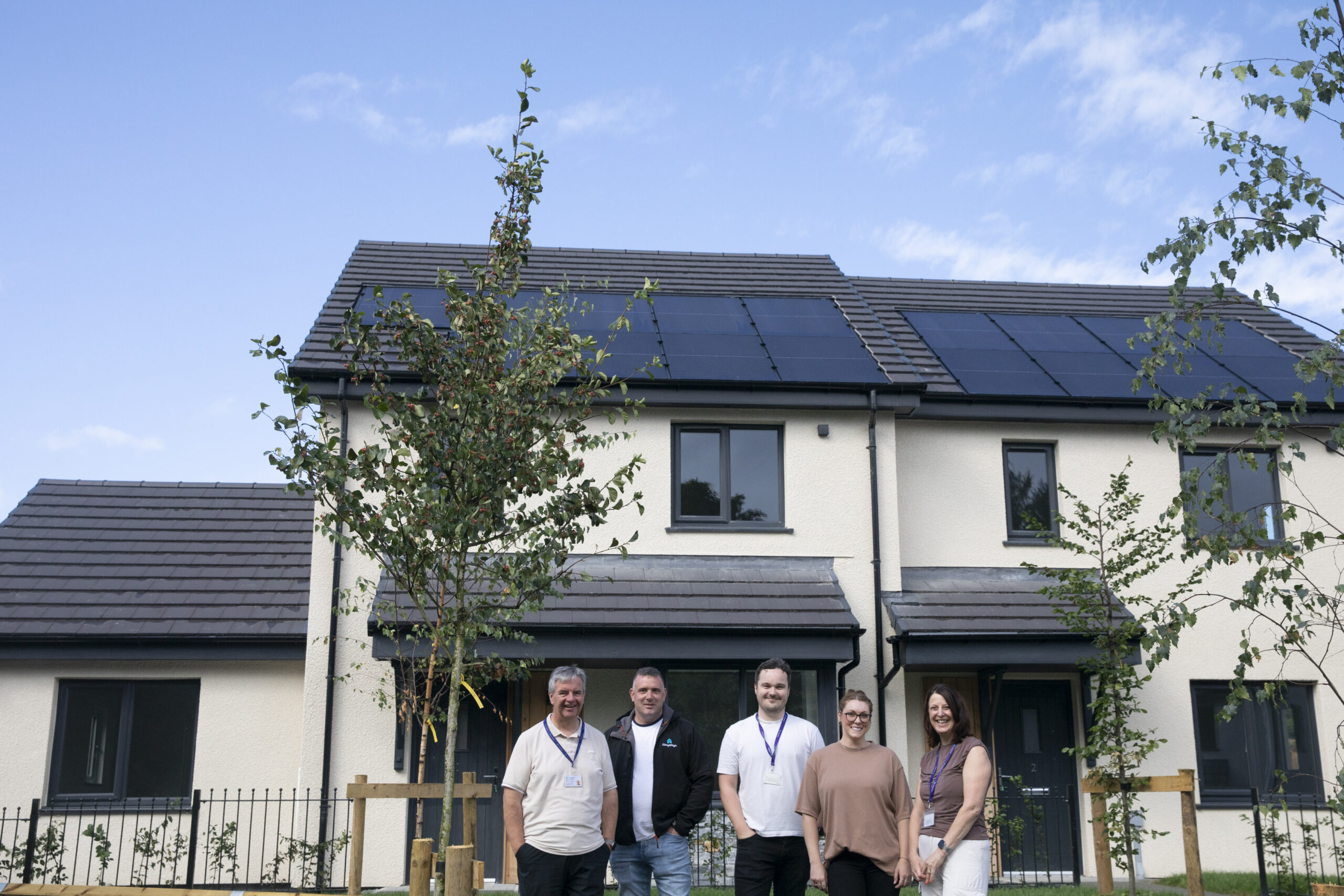 A group of people stand outside a new home.