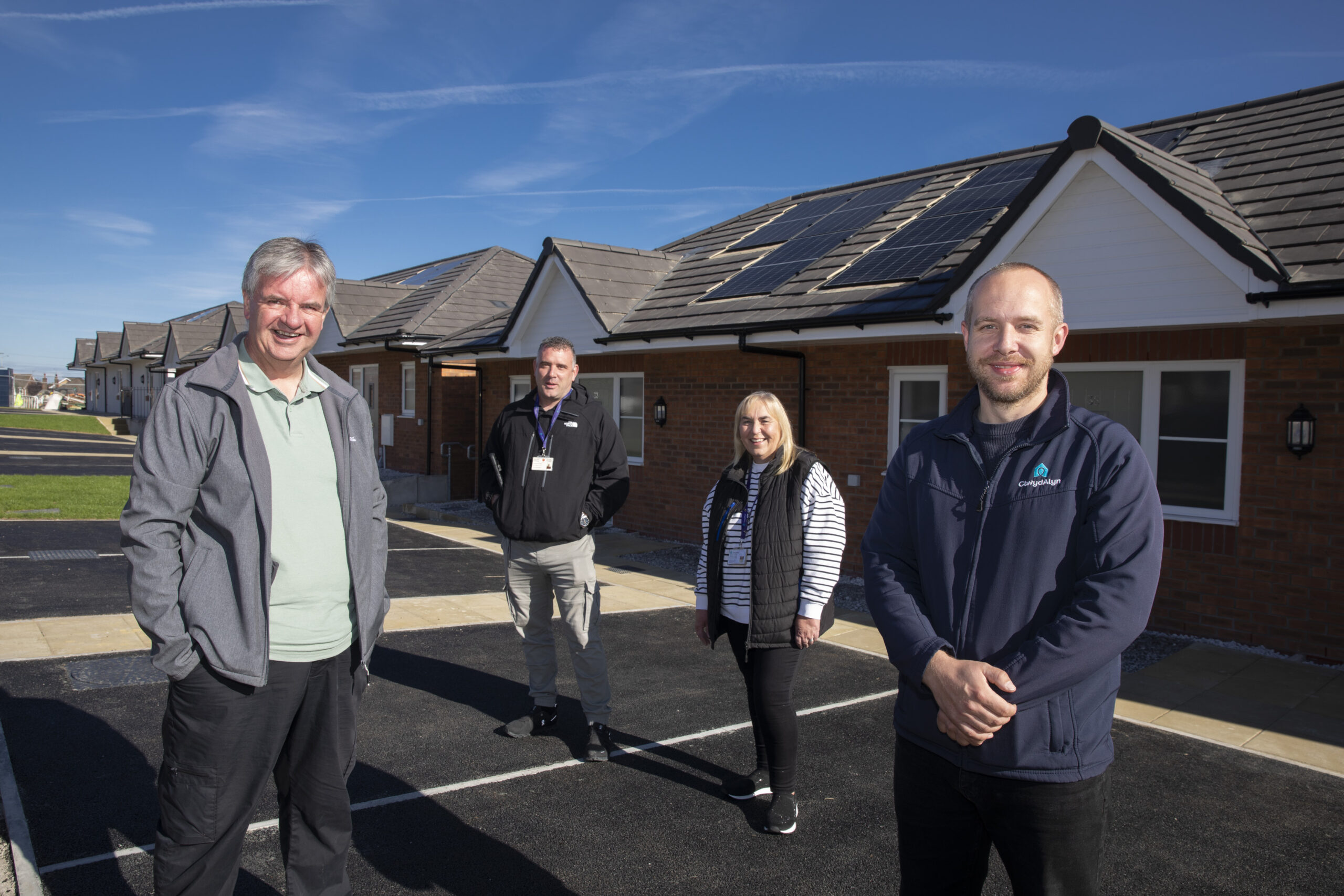 Four people stand outside a new home smiling